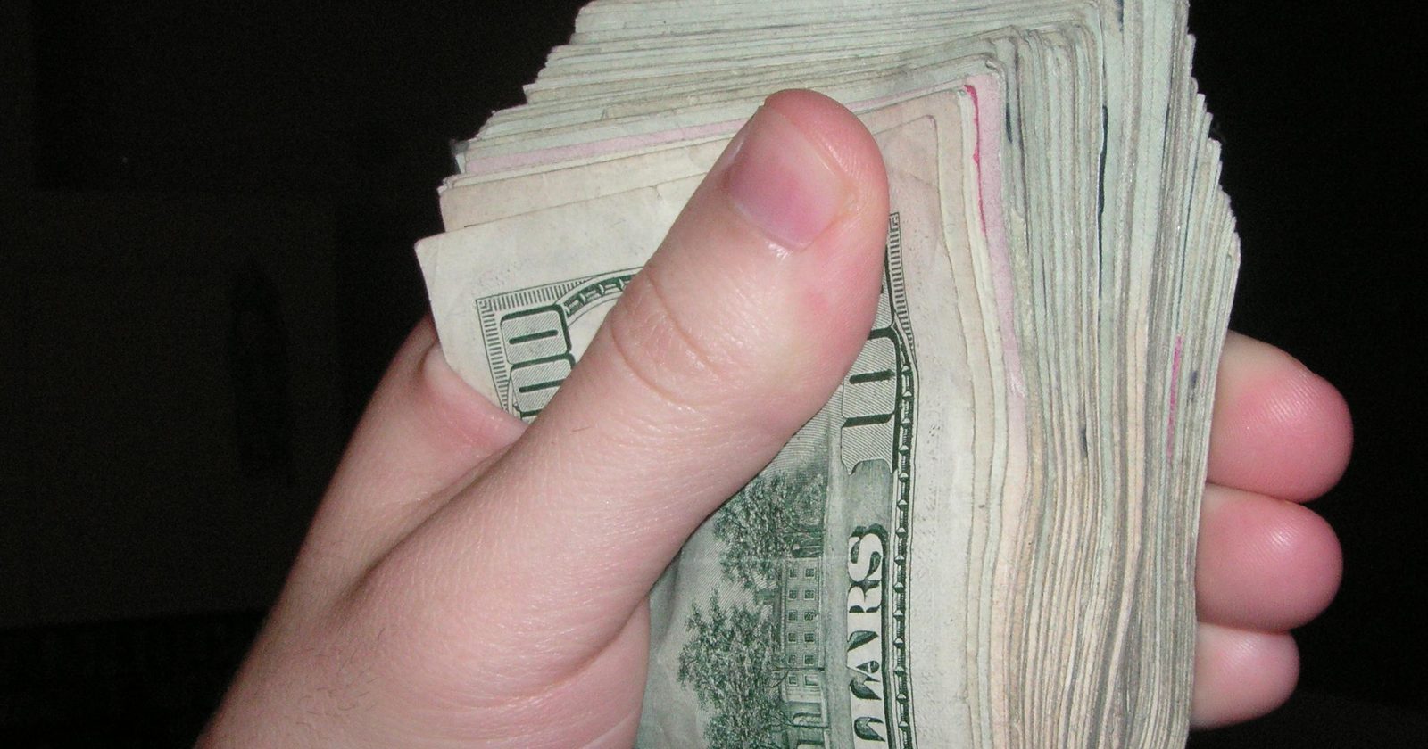 Zwitek banknotów w dłoni — koszt najmu i czynsz w domowym budżecie